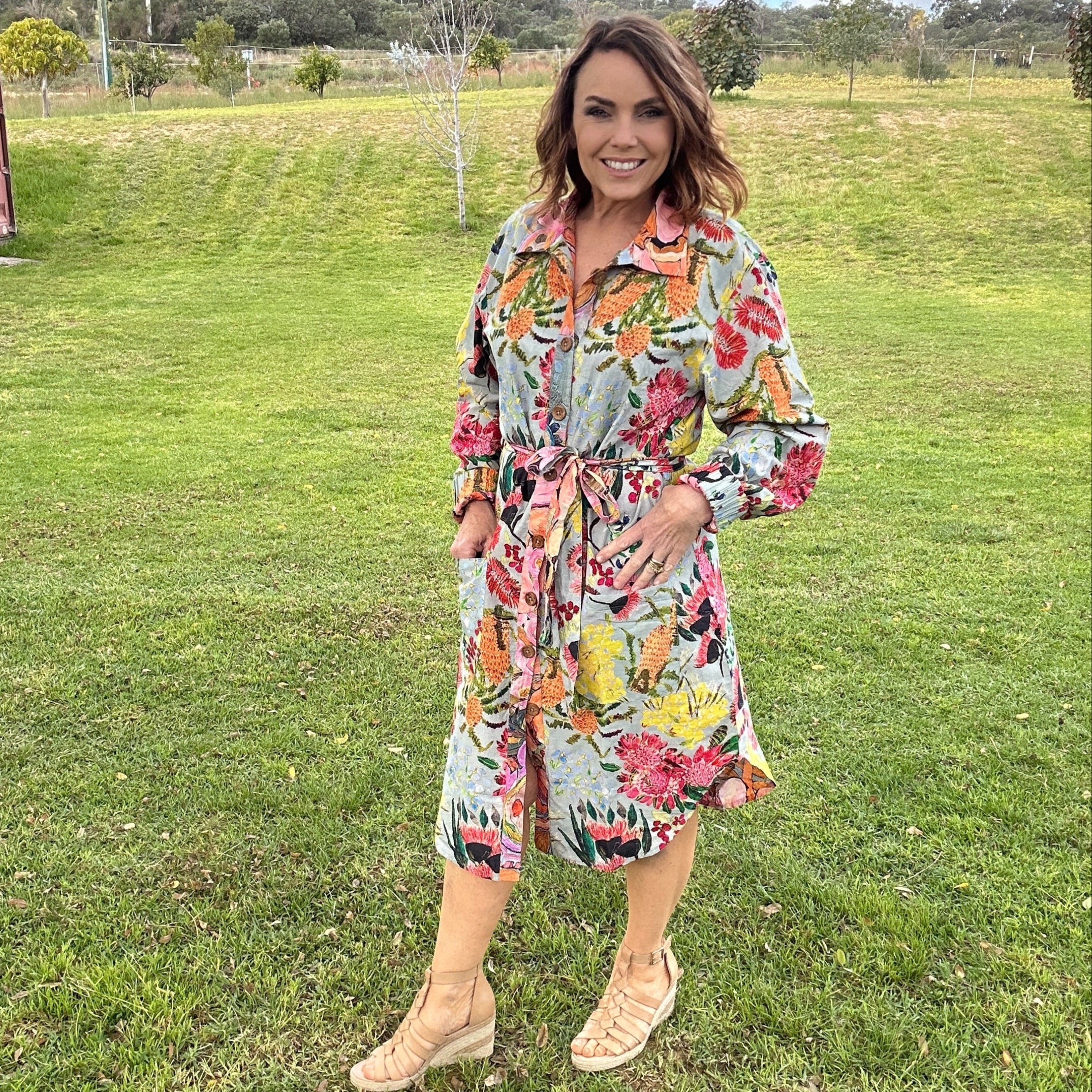 Woman in a floral dress standing on grass with a clear sky