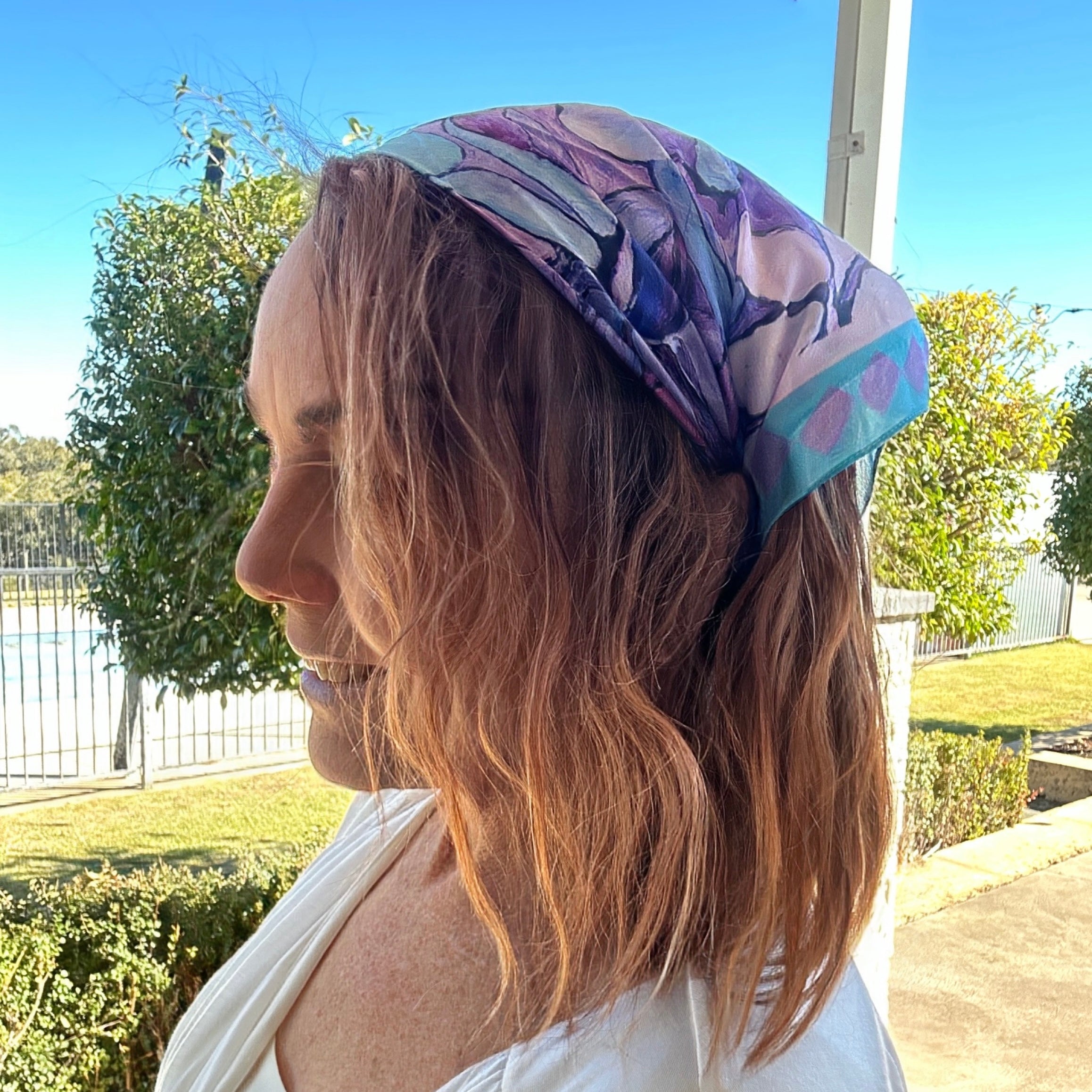 Violet wearable art bandanna with painterly floral artwork worn as a soft artistic women’s headscarf