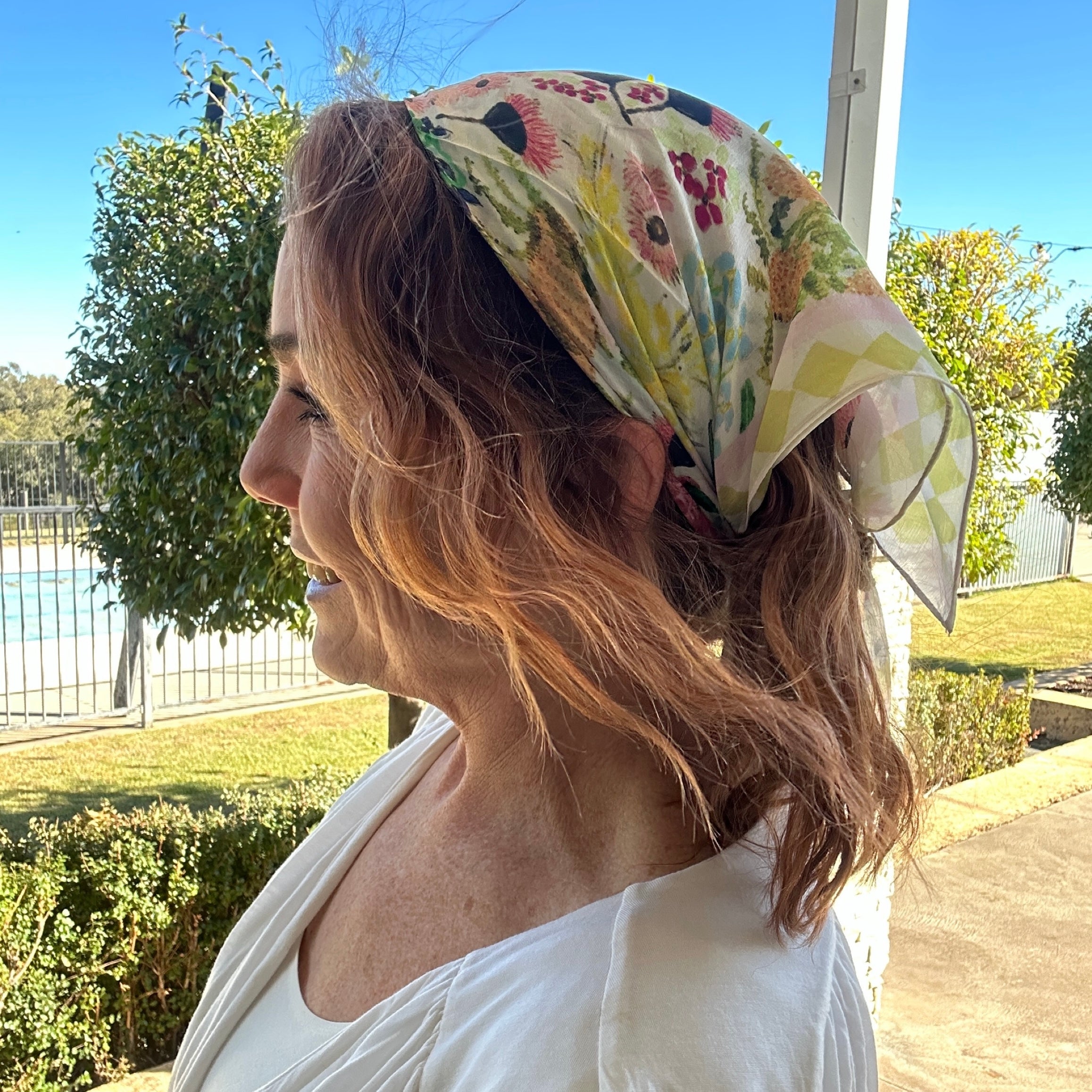 Floral wearable art bandanna featuring soft Australian wildflower-inspired artwork in pastel tones styled as a bohemian hair scarf