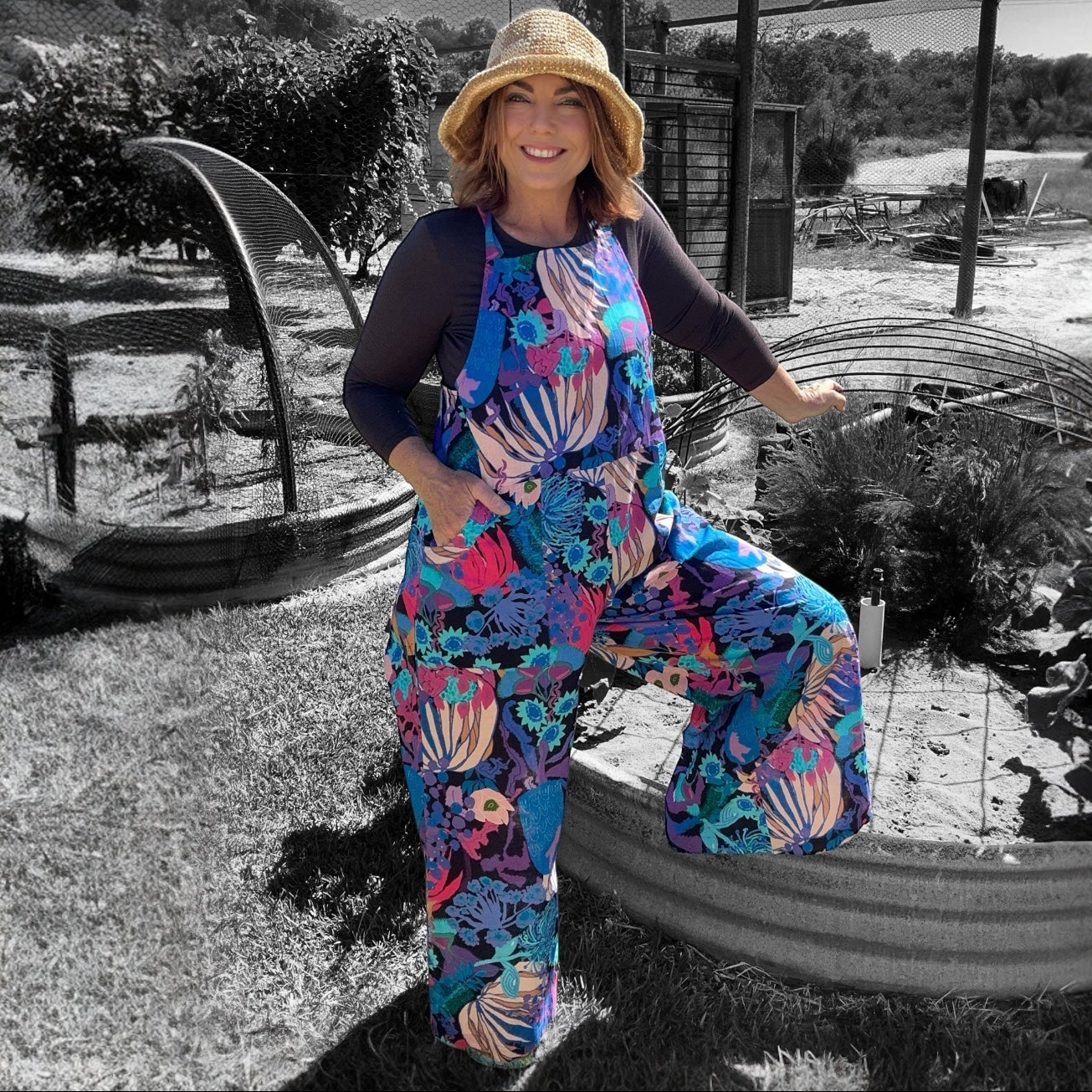 Zoe Playsuit in Bushfire Blues featuring original artwork by Kerry Munns Artlife printed on sustainable linen model standing and leaning on garden
