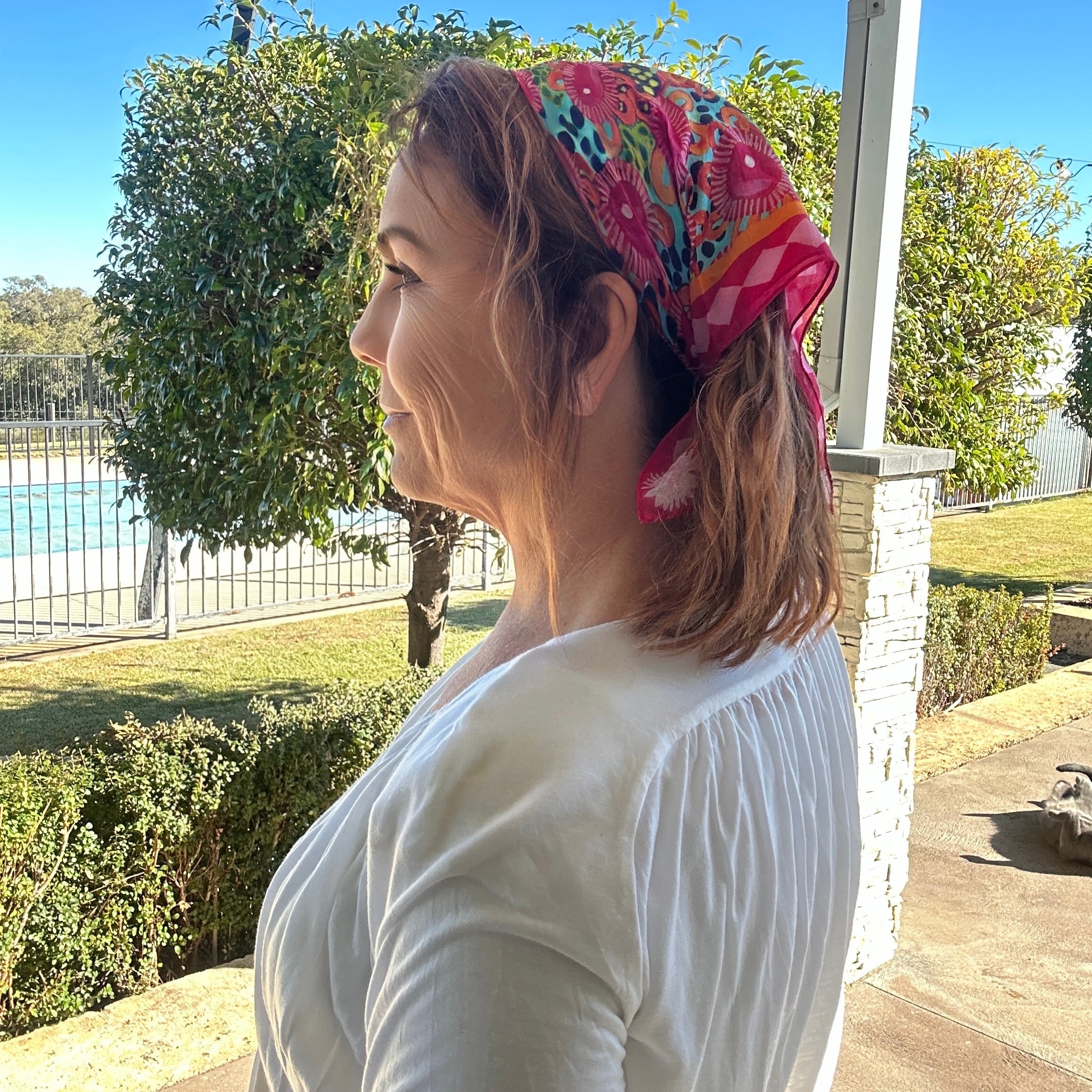 Bright pink floral wearable art bandanna featuring colourful original artwork styled as a vibrant bohemian hair scarf